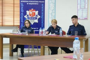 Fotografia przedstawia stół prezydialny, Komendant Komisariatu Policji w Skokach odczytuje sprawozdanie