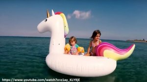 dwójka małych dzieci siedzi na pontonie w kształcie jednorożca, pływają po morzu
