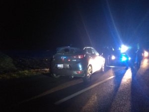 Odzyskany pojazd Mazda Cx3 stojąca na jezdni, w oddali błyski lamp policyjnych