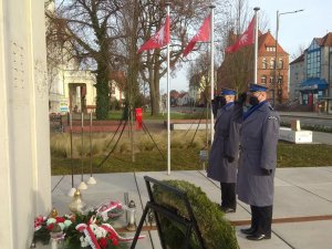 Policjanci oddają hołd przed pomnikiem Powstańców Wielkopolskich i salutują