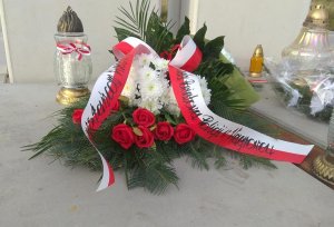 Wiązanka kwiatów leżąca pod pomnikiem, na wstęgach napis &quot;powstańcom wielkopolskim Komenda Powiatowa Policji w Wągrowcu&quot;