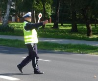fotografia przedstawia policjanta ruchu drogowego zatrzymującego przy użyciu tarczy sygnałowej pojazd