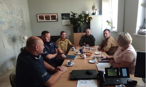 Zdjęcie przedstawia 6 osób biorących udział w spotkaniu - siedzą one  przy stole