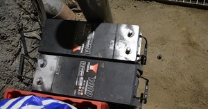 dwa akumulatory od koparki leżą na ziemi przy ścianie widok z góry