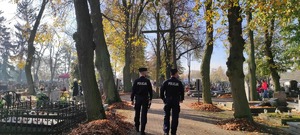 Policjanci idą aleją cmentarną