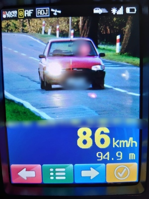czerwony samochód w kadrze urządzenia i zmierzona prędkość 86 km/h