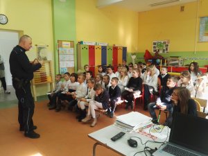 Dzielnicowi prowadzą zajęcia dla dzieci, dzieci na miejscach wysłuchują pogadanki aspiranta sztabowego Dariusza Szymczaka