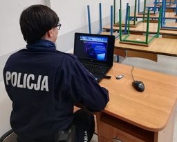 policjantka siedzi przy biurku przy laptopie i prowadzi zajęcia online