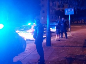 Policjanci z zatrzymanymi na gorącym uczynku, stoją obok radiowozu i ich pojazdu, jest noc, widać światła policyjnych radiowozów.