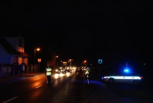 Fotografia przedstawia policjantów badających trzeźwość kierowców na drodze.