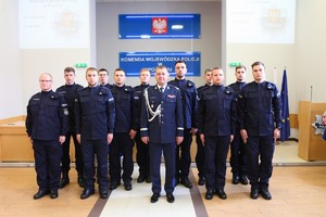 Policjanci  z komendantem Wojewódzkim Policji stoją do zdjęcia, w tle baner KWP w Poznaniu