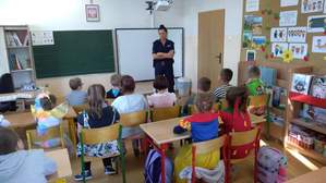 Policjantka w klasie prowadzi zajęcia dla dzieci, dzieci siedzą w ławkach