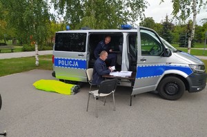 Radiowóz stoi na placu, przy nim rower i policjanci