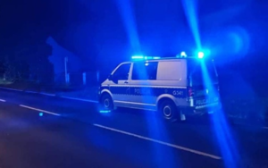 radiowóz stojący przy ulicy nocą z włączonymi niebieskimi światłami