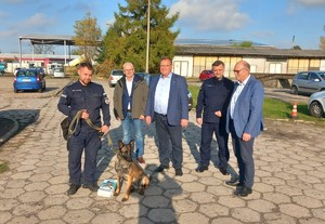 Przewodnik psa stoi z psem przy nodze, obok nich stoją władze gminy Wągrowiec - wójt, przewodniczący rady gminy, i zastępca wójta i komendant policji w Wągrowcu.