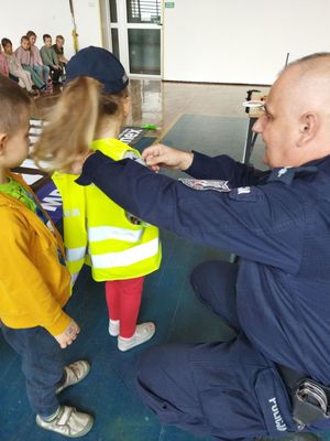 policjant zakłada dziecku kamizelkę odblaskową