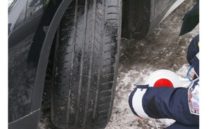 policjant przygląda się stanowi ogumienia opon