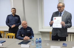zdjęcie stołu prezydialnego, na fotografii widać dwóch policjantów - komendanta powiatowego i komendanta wojewódzkiego i przemawiającego wicestarostę