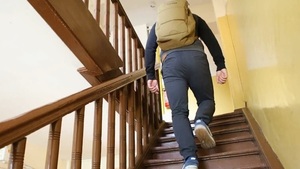mężczyzna z plecakiem wchodzi po schodach w kamienicy
