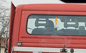 Fotografia szoferki, widać jak kierowca rozmawia przez telefon komórkowy, trzymając go przy głowie