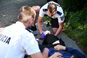 policjanci udzielają pierwszej pomocy leżącej krwawiącej osobie