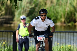 rowerzysta policjant na trasie przejazdu, wykadrowany portret , w tle widać policjanta z ruchu drogowego