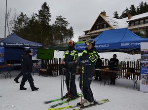 policjanci na nartach jadą po stoku