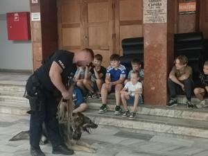 policjant z psem służbowym przed dziećmi, głaska go