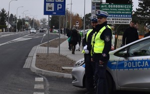 policjanci wrd przed radiowozem obserwują ruch na drodze