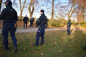 policjanci stoja na trawniku, w oddali jest stadion