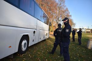 policjanci stoja przy autokarze z kibicami