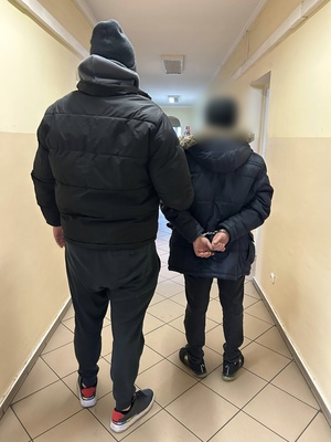 policjant w korytarzu stoi z zatrzymanym