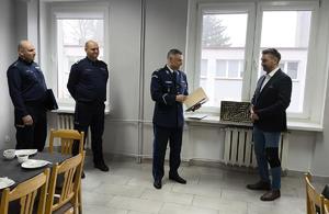 komendant dziękuje policjantowi obok, który odzesdł na emeryture. trzech policjantów w mundurach, jeden w garniturze emeryt