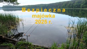 kadr na stanowisko wędkarskie nad jeziorem, przy nim dwie wędki  i napis bezpieczna majówka 2025