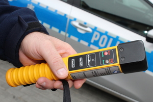policjant trzymający urządzenie do badania alkoholu w dłoni