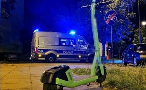 hulajnoga stojąca na chodniku, w tle radiowóz na sygnale