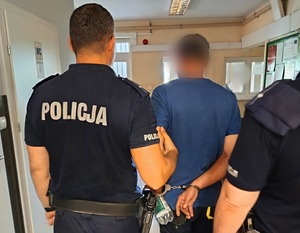 policjanci prowadza zatrzymanego korytarzem