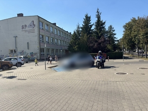 policjant na motocyklu z włączonymi światłami przy szkole stoi przy miejscu parkingowym dla niepełnosprawnych