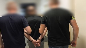 policjanci prowadzą jednego z zatrzymanych