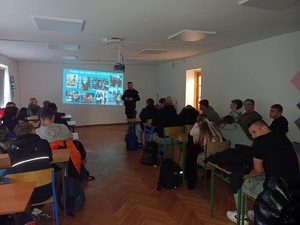 policjant stoi przed młodzieżą obok prezentacja