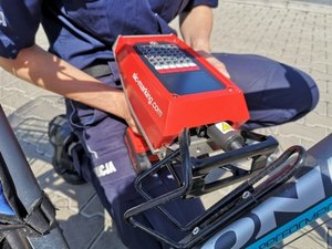 policjant znakuje rower, trzyma maszynkę do znakowania