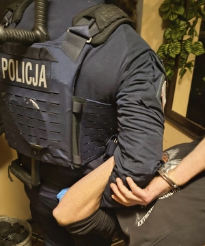 Policjanci trzymają w chwycie transportowym zatrzymanego