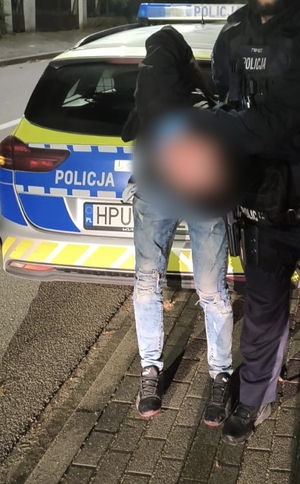 Policjanci trzymają w chwycie transportowym zatrzymanego