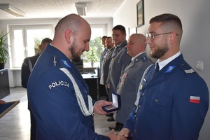 zdjęcia ze zbiórki, policjanci odbierają wyróżnienia- rozkazy, przypinane są im medale związkowe, a także pozują do zdjęć grupowych z przełożonym po otrzymaniu wyróżnień