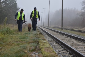 policjanci wraz z psem służbowym patrolują tereny przy torowisku