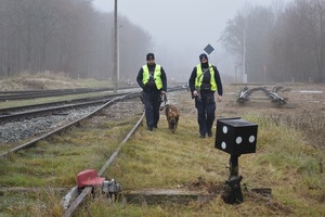 policjanci wraz z psem służbowym patrolują tereny przy torowisku