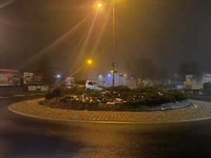 samochód na nasypie ronda, obok niego radiowóz i pojazd pomocy drogowej