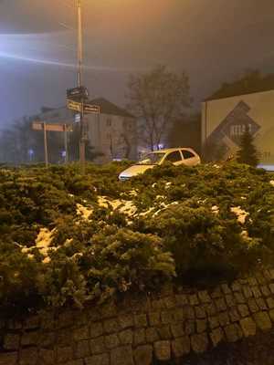 samochód na nasypie ronda, obok niego radiowóz i pojazd pomocy drogowej