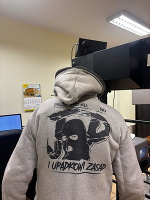 lichtarze i krzyże zabezpieczone przez policjantów, zatrzymany w bluzie, zatrzymany prowadzony przez policjantów na ulicy