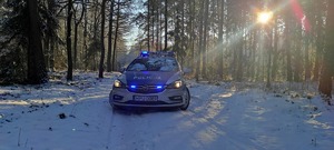 radiowóz policyjny stoi w lesie w śniegu